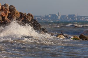 Rock with sea waves against a town